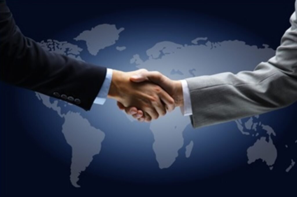 two-people-in-suits-shaking-hands-over-a-blue-world-map-background