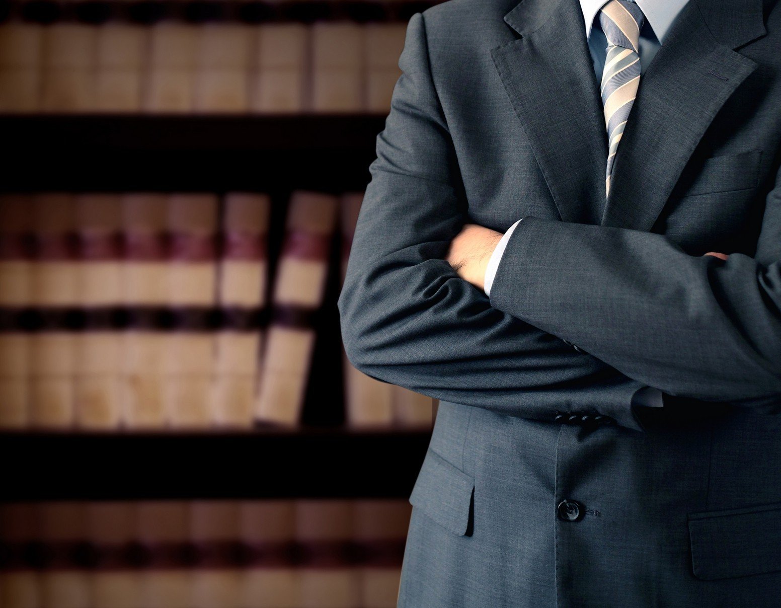 man-in-suit-with-arms-crossed-standing-in-front-of-law-books-bookshelfman-in-suit-with-arms-crossed-standing-in-front-of-law-books-bookshelf