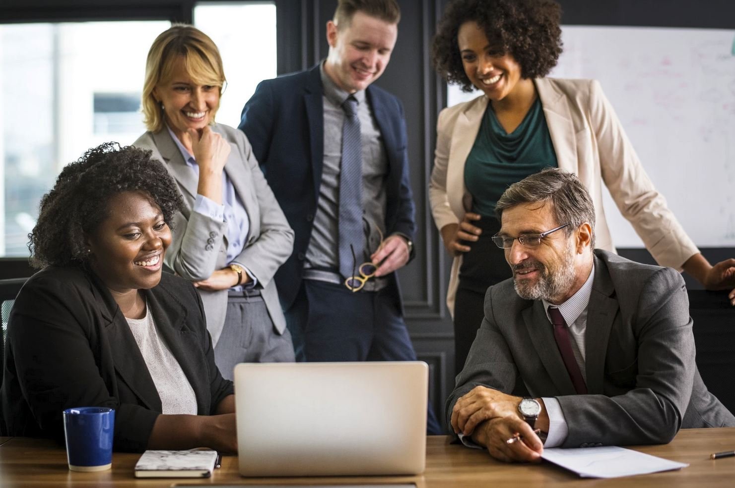 diverse-business-team-smiling-around-laptop-in-office