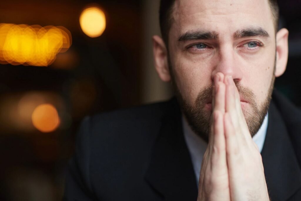 man-in-suit-with-hands-pressed-together-looking-downcast